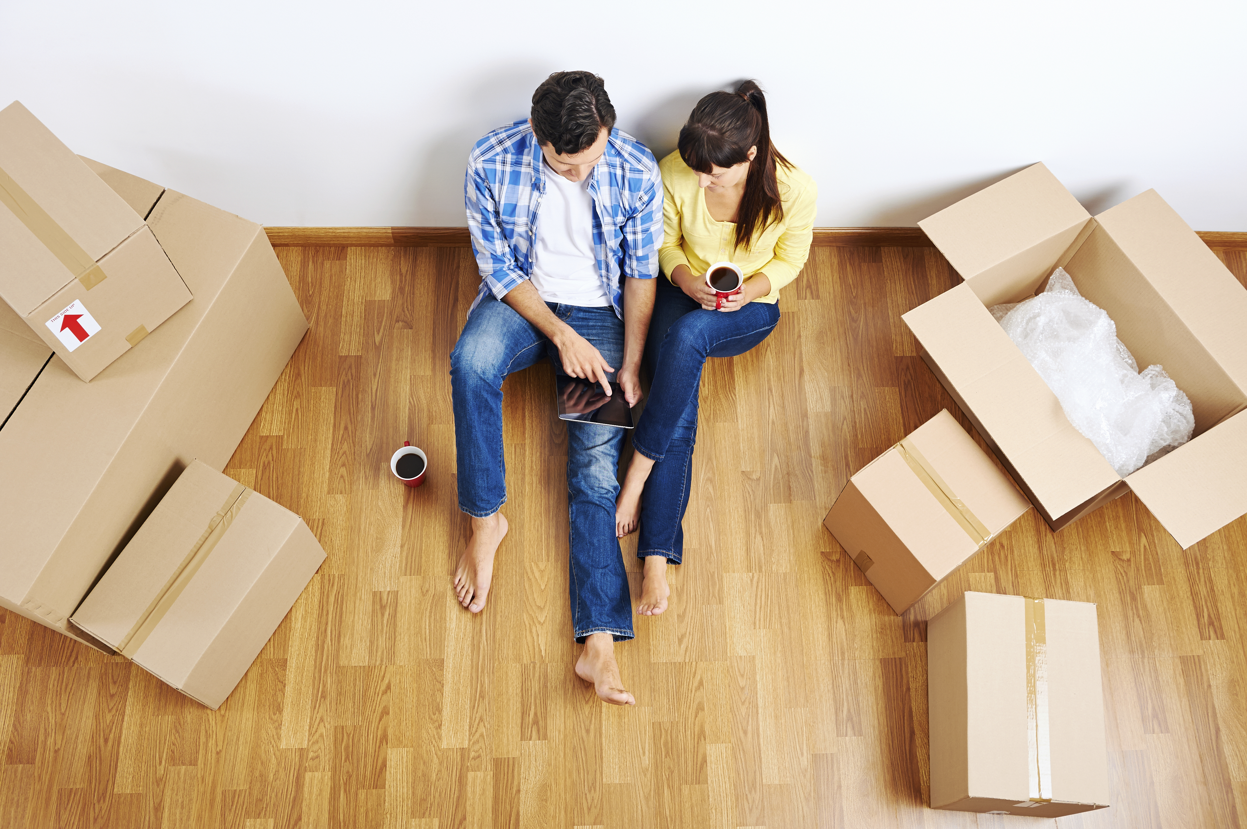 overhead view of couple moving in to new home and using wireless internet on tablet computer
