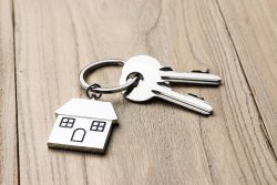keys attached to a house-shaped keyring on a wooden background